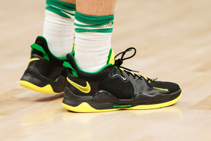 View of black, yellow, and green Nike shoes.